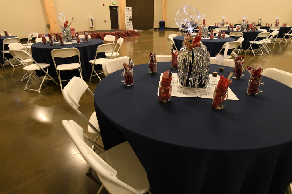 Event in the banquet room with blue tablecloths and red accents on the tables