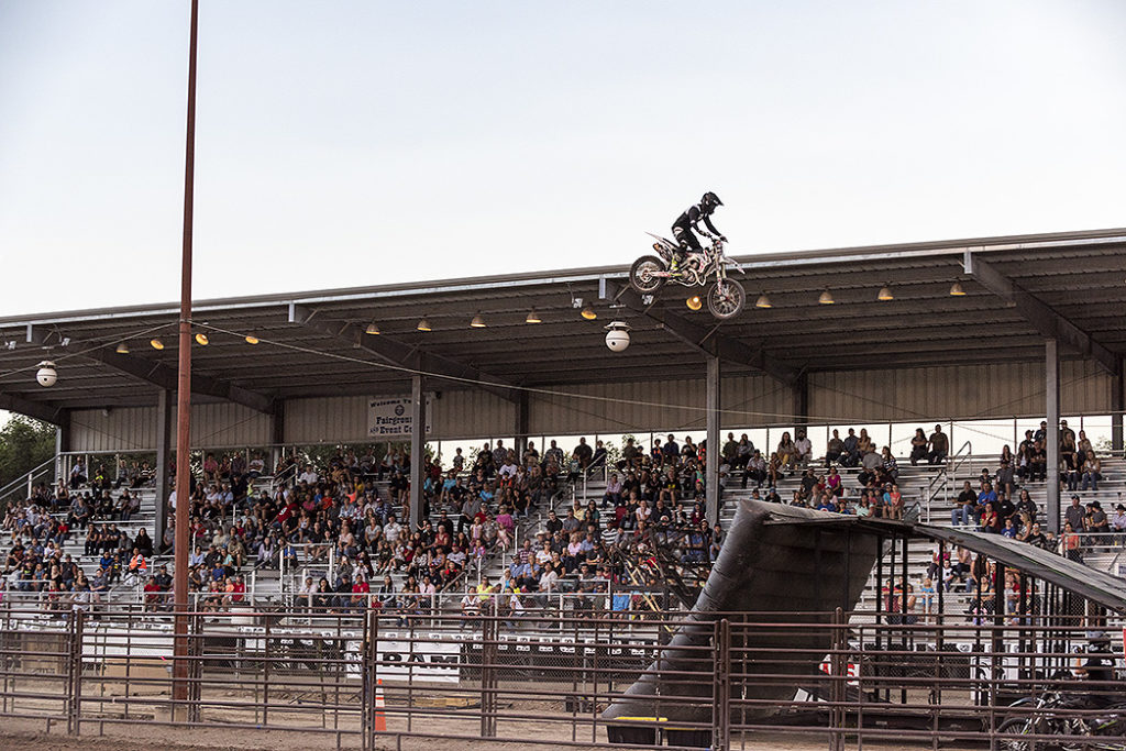 Montrose County Fairgrounds with motorcycle doing stunt jumps with crowd in stadium in background
