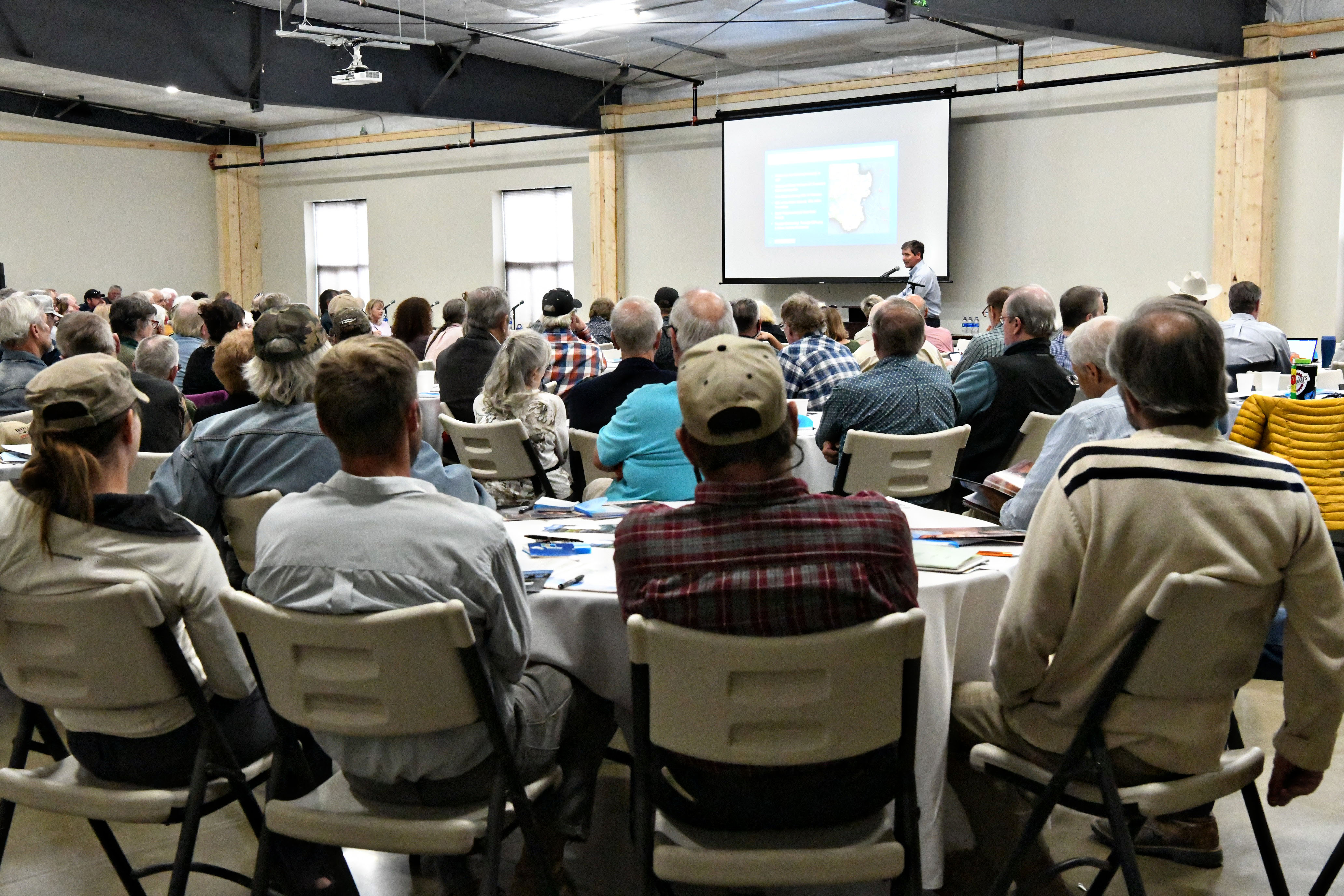 photo of people sitting at tables at conference at the event center listening to speaker