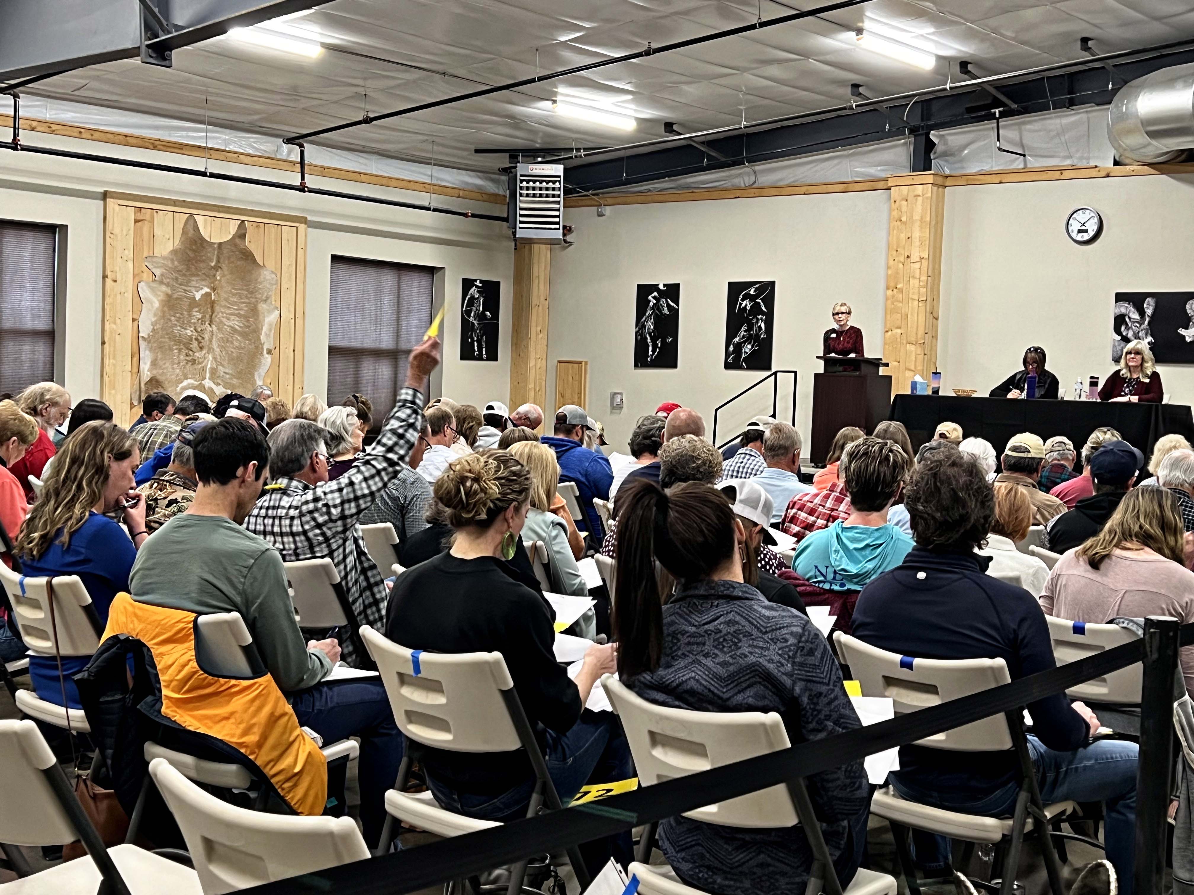 many people sitting in chairs at an auction in the banquet room