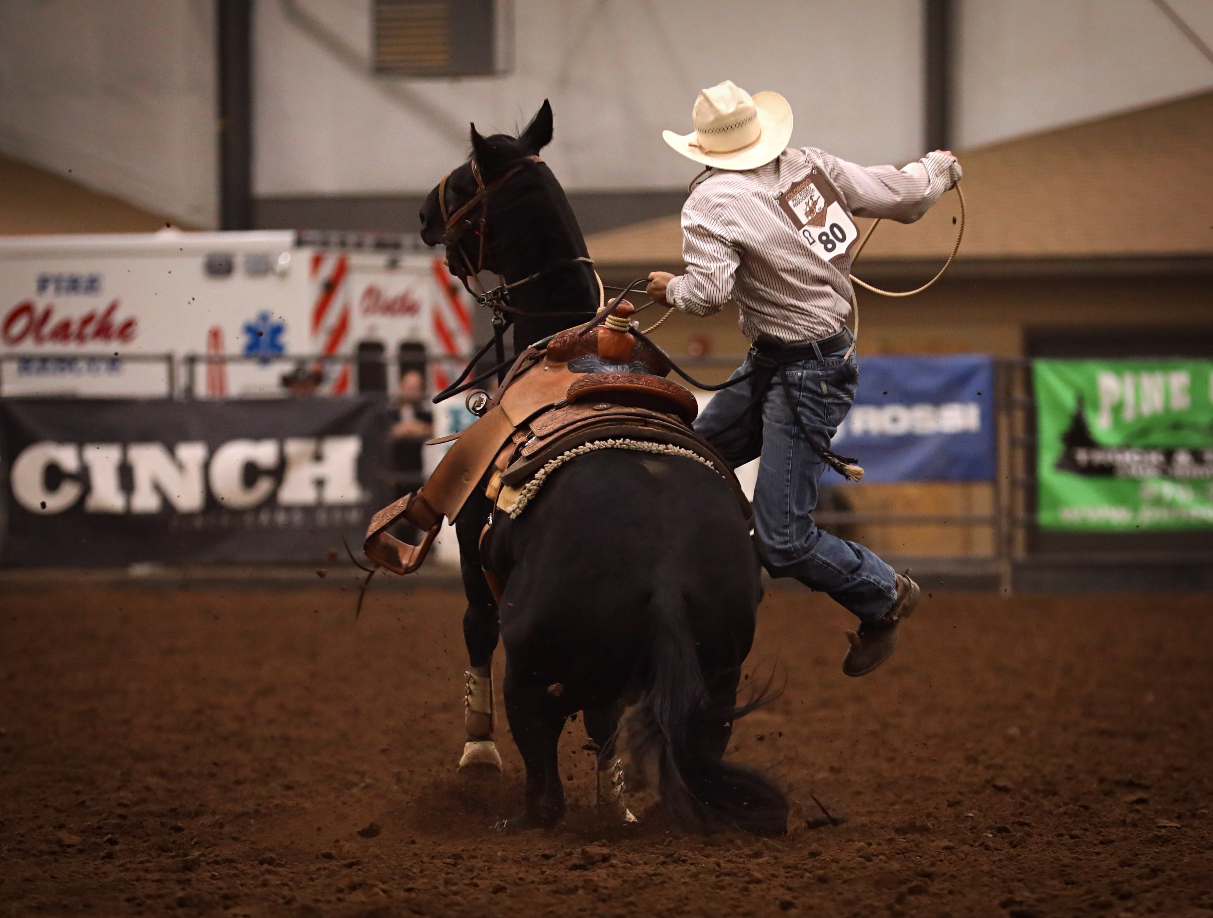 man jumping off horse during roping event